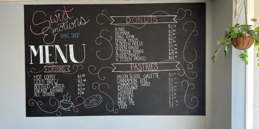 A black chalkboard lists menu items among banner headings and decorative swirls.
