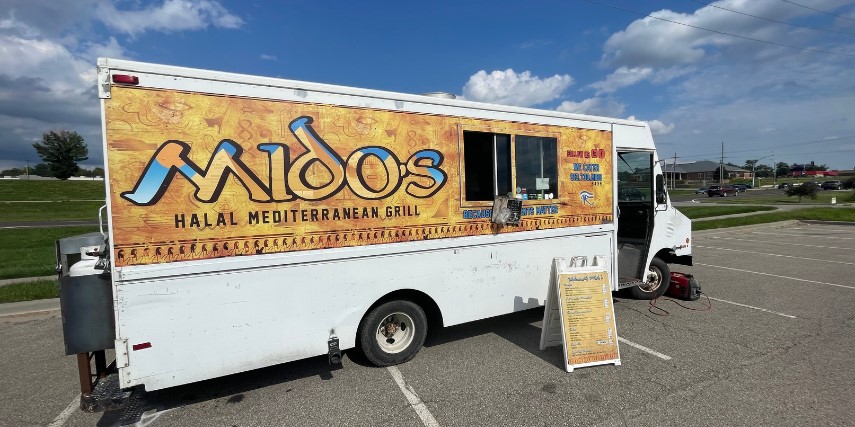 Food truck with the name "Midos" written across a beige backdrop.