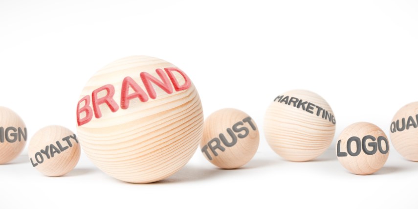 Wooden balls of different sizes on a white background with words printed on them. The largest ball has "brand" written on it.