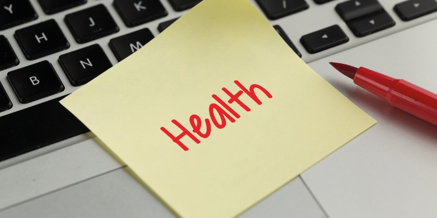 A yellow Post-It note with the word "health" written on it in red is stuck to a keyboard.