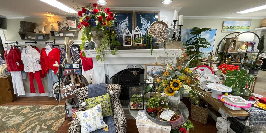 A fireplace and chair anchor a display of home decor and fashion goods.