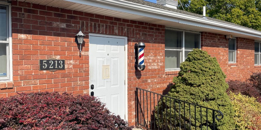 Front door of Hickman's Barber Shop with the barber shop pole visible near the door. 