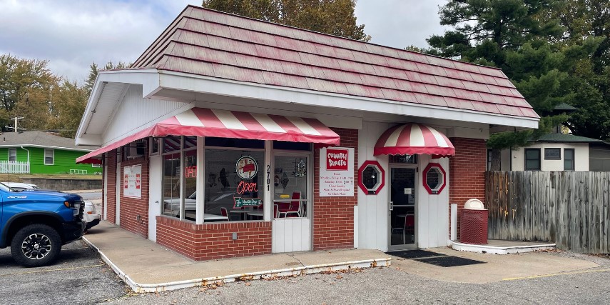 Outside view of Crumbly Burger restaurant, with red and white awnings and red trim on a white building.