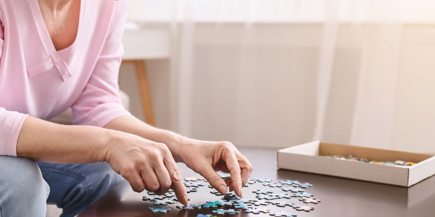 Close-up of a table surface where a woman is working on a puzzle.