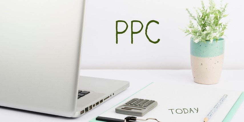 A laptop, calculator and clipboard are on desk with the acronym "PPC" in the background.