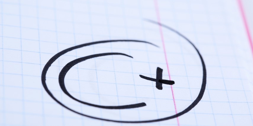 A school paper has "C+" written and circled in black marker.
