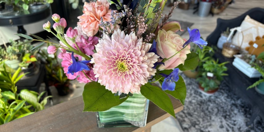A flower arrangement shows pink and blue flowers with green leaf accents.