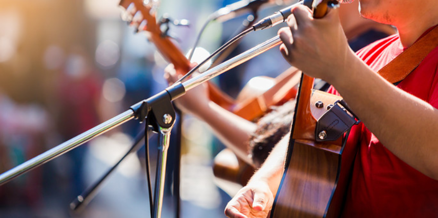 Close-up of musicians' instruments and microphones as they perform at a concert.